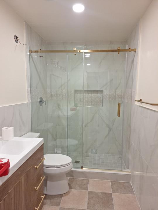 Marble-look tile shower with a brushed-gold sliding door
