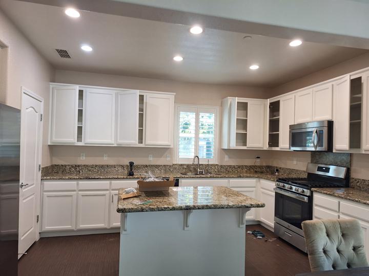 Kitchen cabinets painted white, with recessed ceiling lights